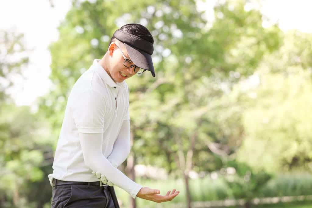 male golfer grabbing painful elbow